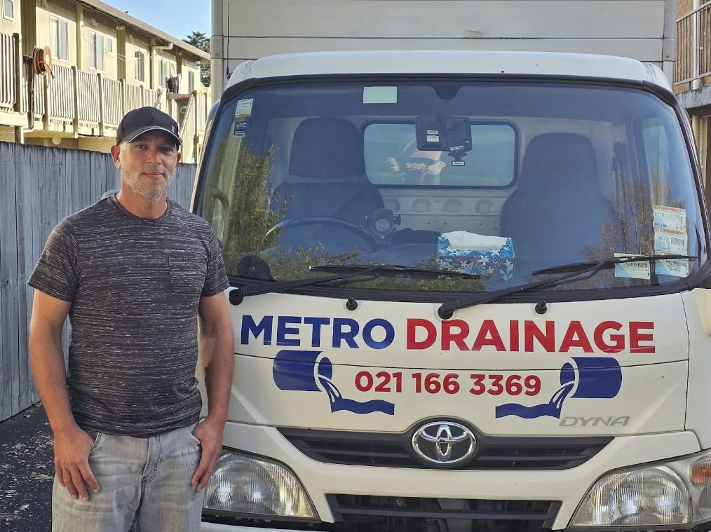 Metro Drainage owner standing in front of the company truck