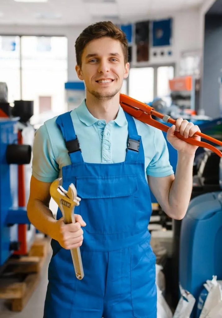 Smiling plumber holding a pipe wrench and spanner