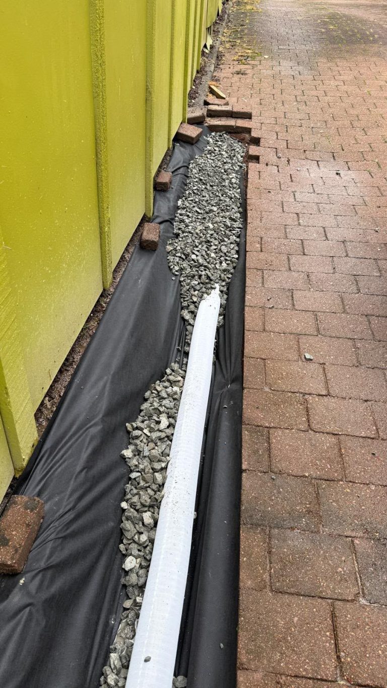 Commercial drainage pipe laid on building wrap beside a wall