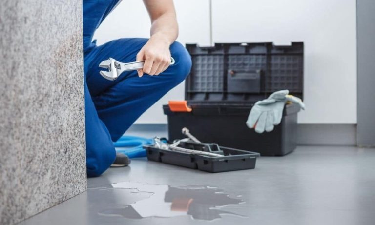Plumber with a toolbox repairing commercial drainage pipework